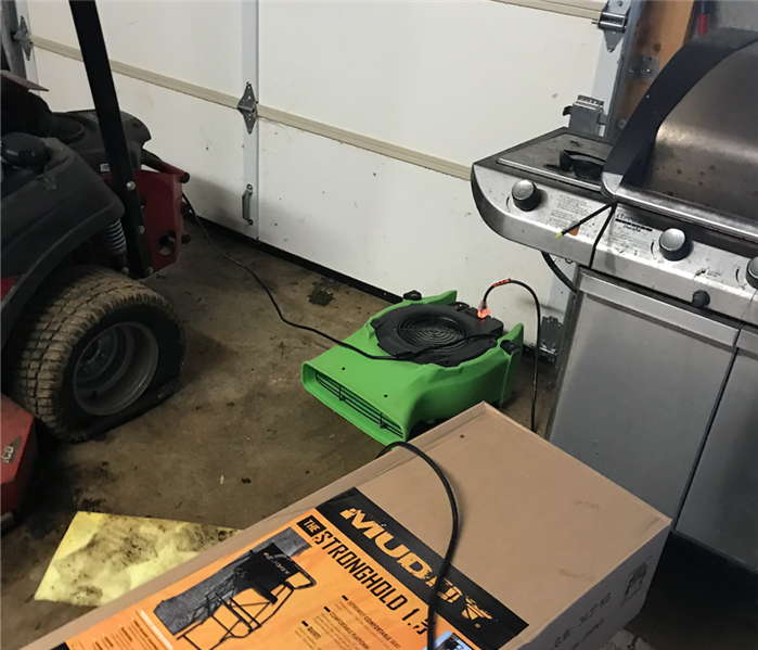 SERVPRO equipment sitting in garage floor that was flooded from a storm's heavy rain.
