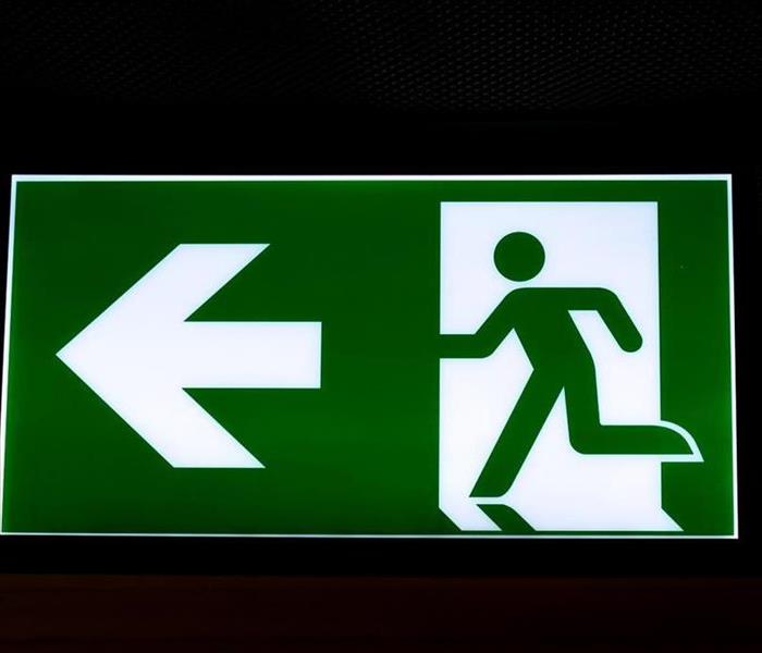 Green exit sign with arrow pointing to left with icon of a person running for safety.