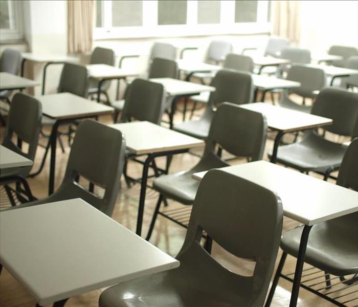Rows of empty school desks sitting in an empty classroom.